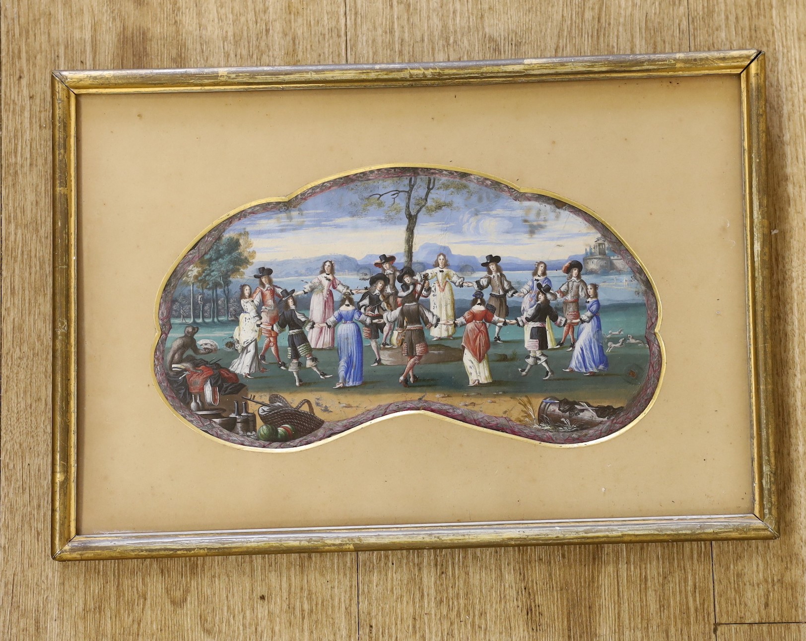 Early 18th century Flemish School, gouache, Figures dancing in a coastal landscape, cartouche shaped, 14 x 26cm